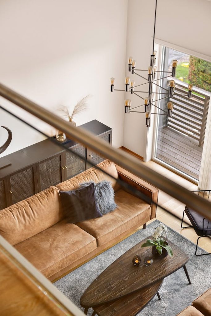 Stylish living room with a brown couch, elegant chandelier, and a cozy interior design.